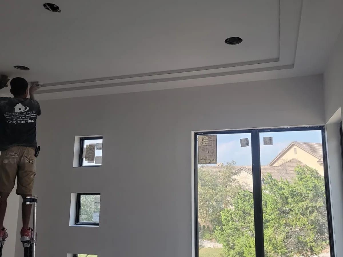 Finisher on stilts working a ceiling line